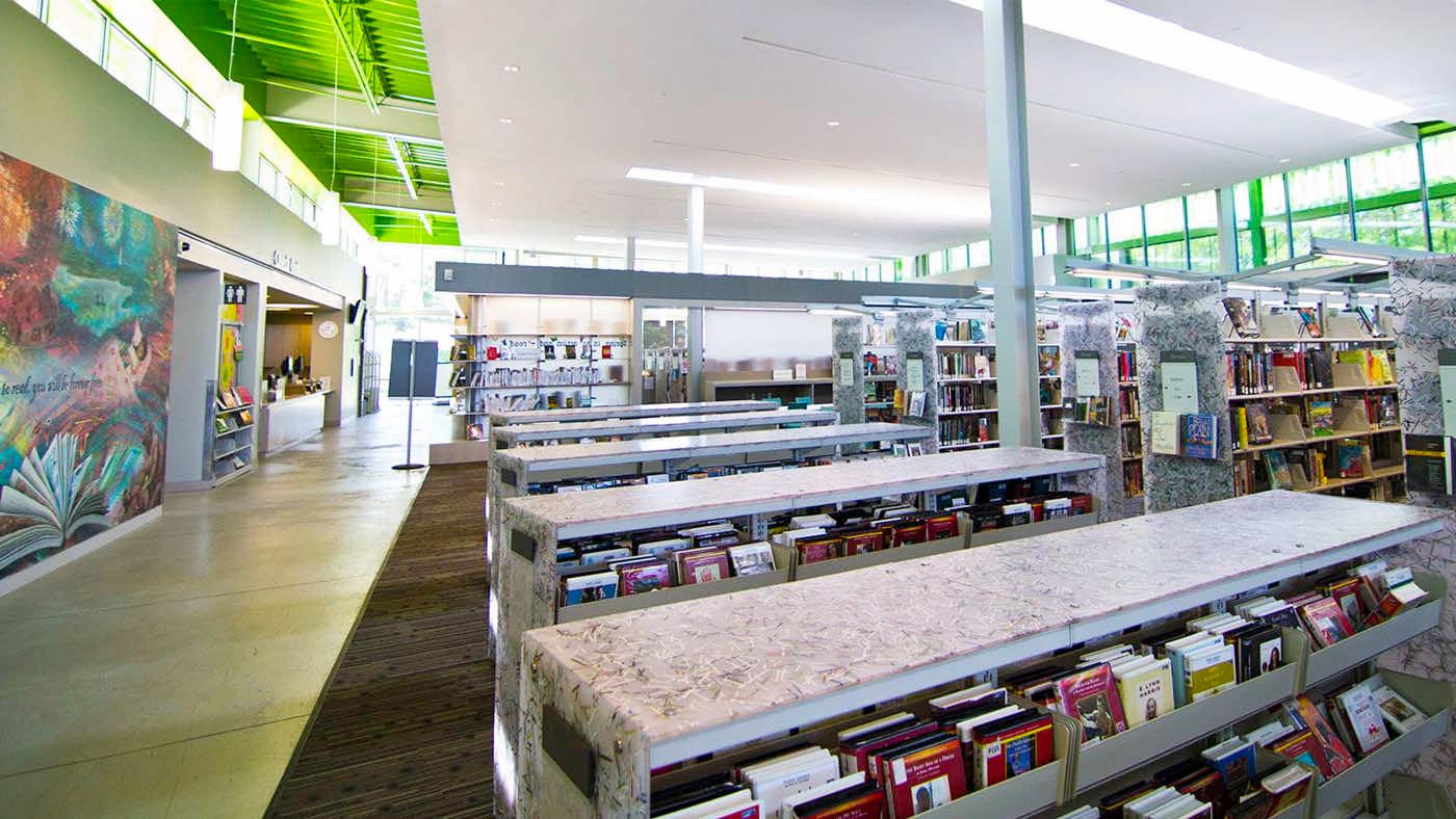 Library with multiple book shelves and flexible shelving units next to mural on wall